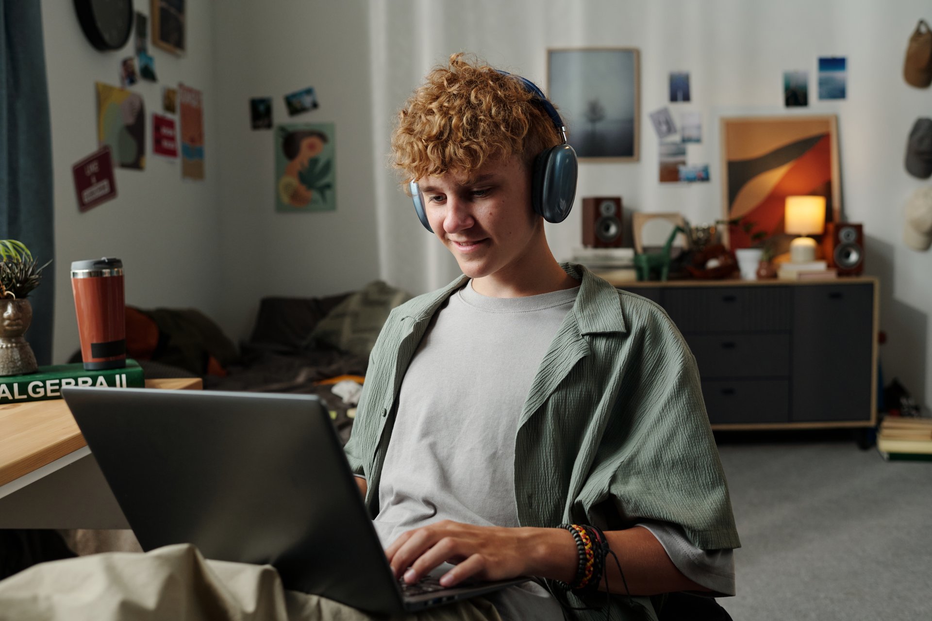Teenage boy with headphones using laptop, engaged in digital learning and personal development