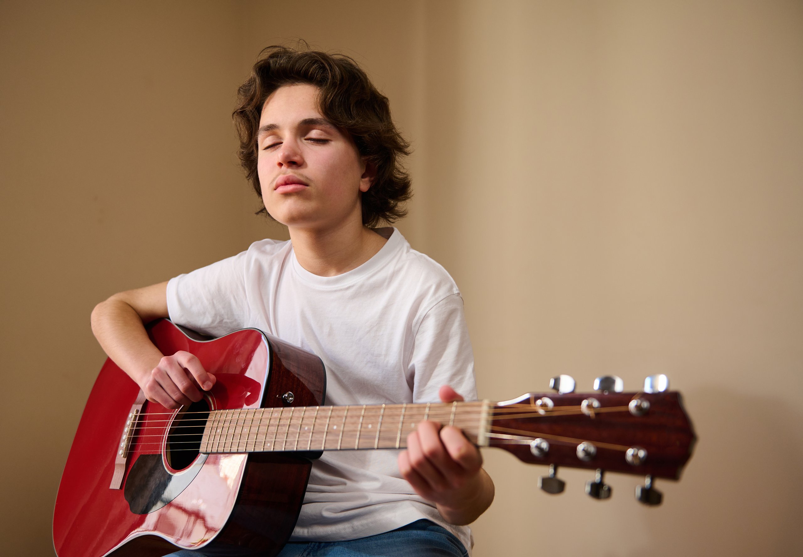Teenage boy playing acoustic guitar, creative expression and skill development